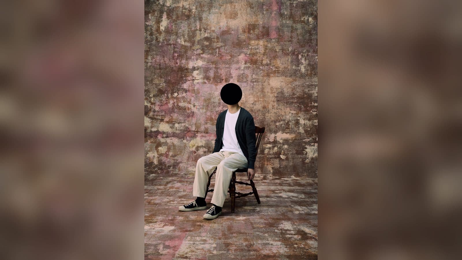 恐怖心展主視覺:一名面容被黑色圓形遮蔽的人,靜靜坐在椅子上